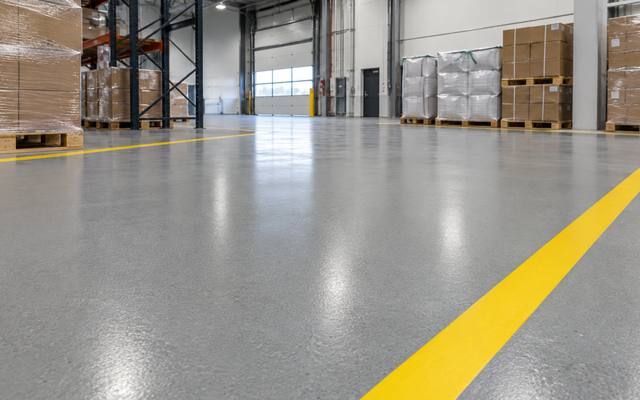 Warehouse floor coating with a yellow lane line across a pallet staging area in Oxford County